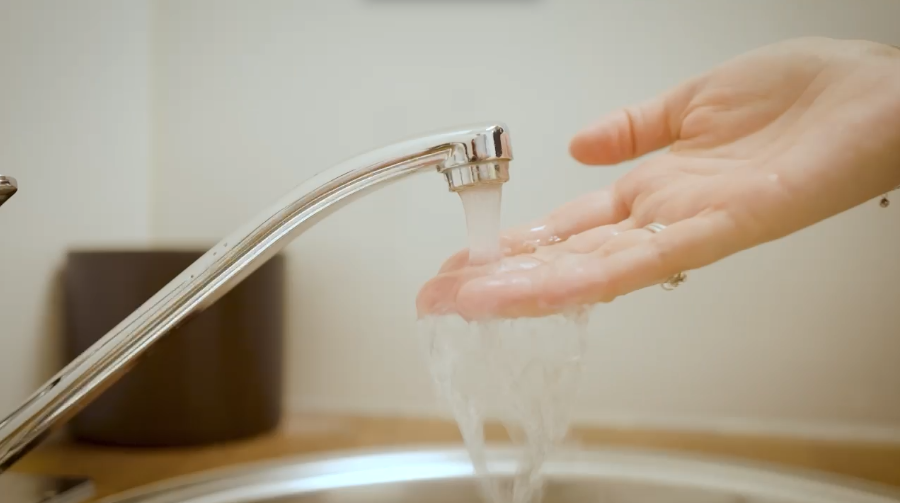 hand onder stromende kraan om te voelen of het water warm is.
